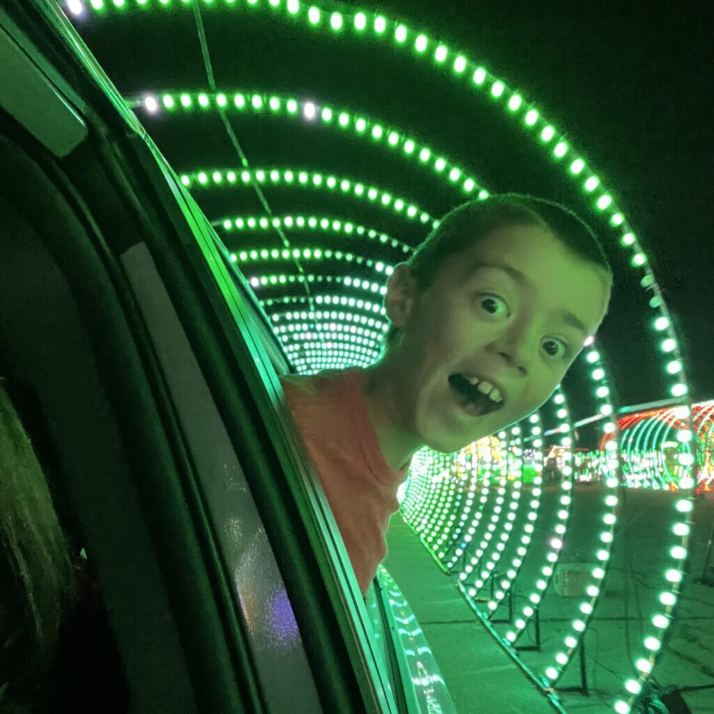 kid sticking head out of car window in a light tunnel