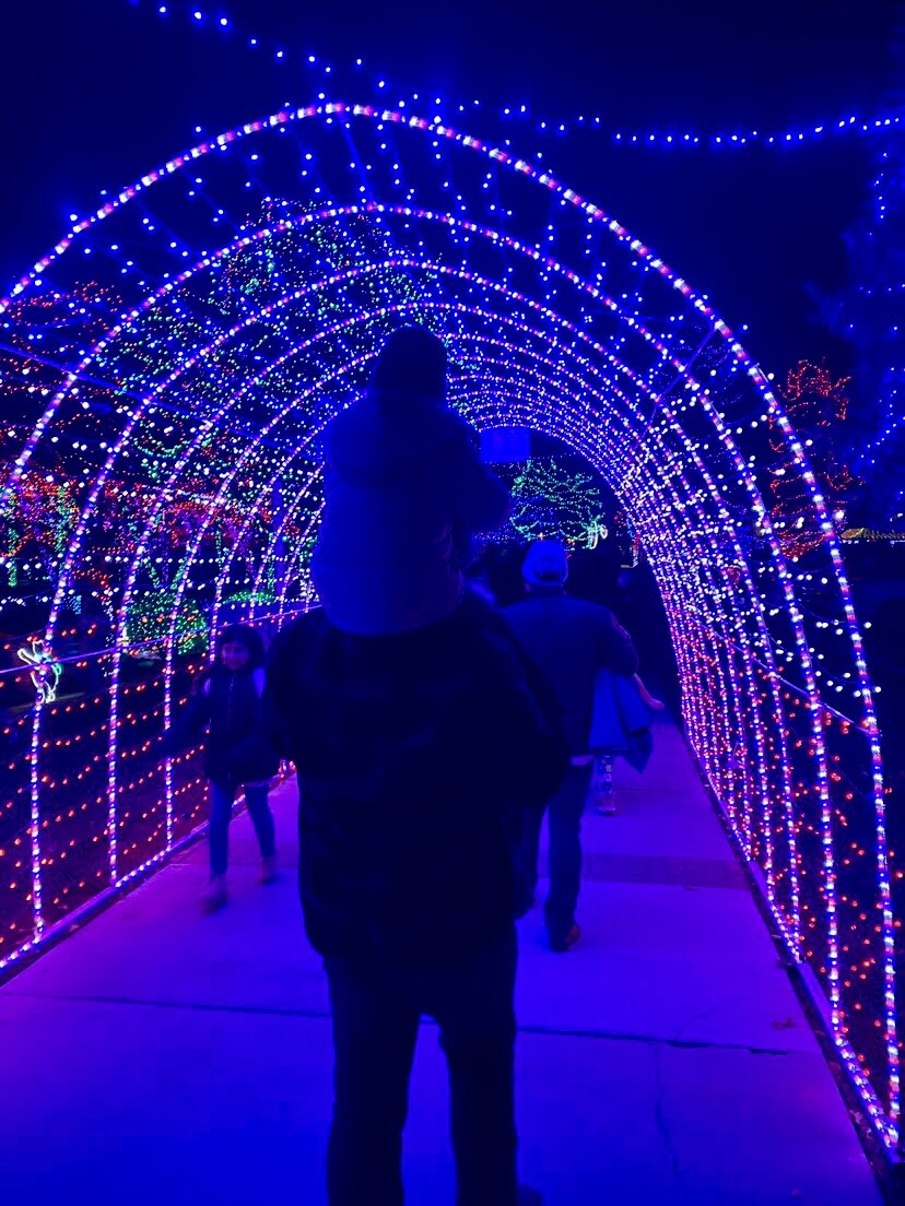man walking through light tunnel with kid on shoulders
