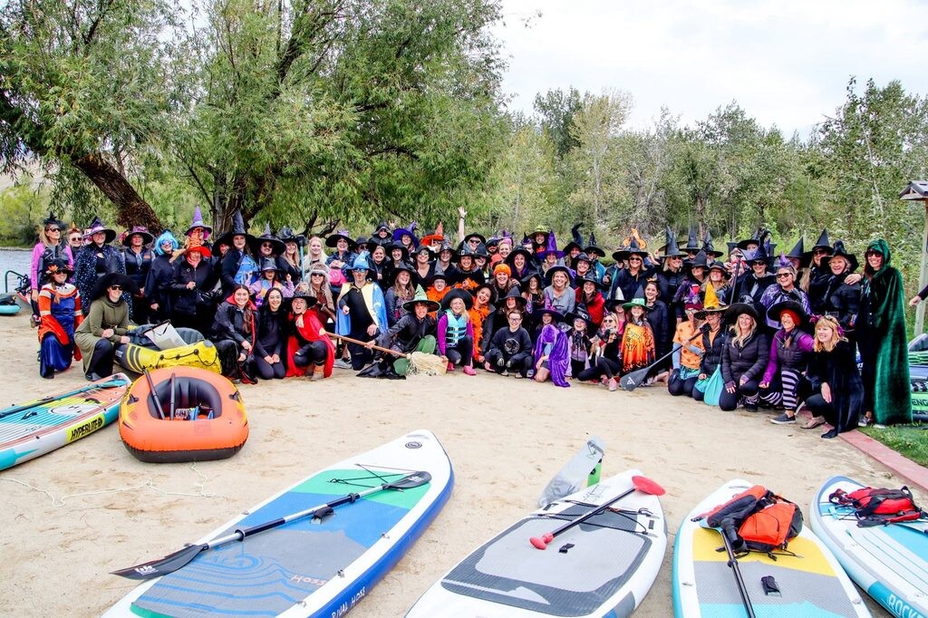People dressed up as witches in front of paddle boards